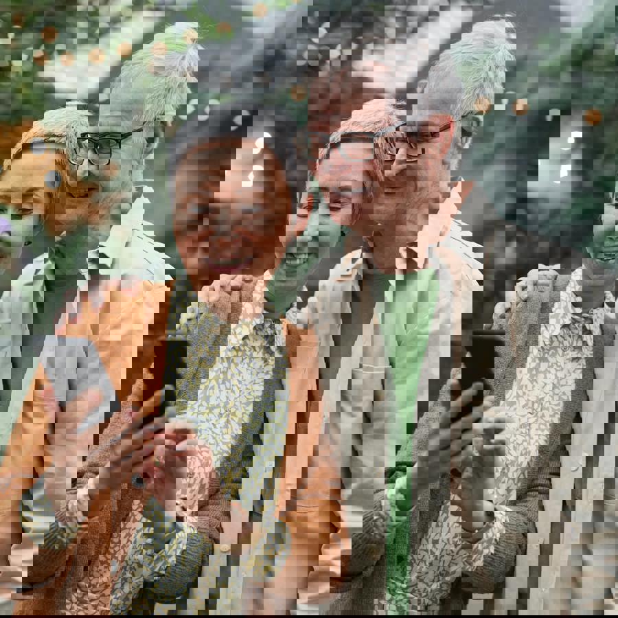 Echtpaar dat buiten op een telefoonscherm kijkt Echtpaar dat buiten op een telefoonscherm kijkt