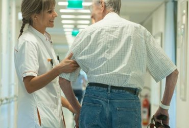 Verpleegkundige helpt bejaarde man met lopen 