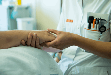 Een foto van handen die verzorgd worden door een verpleegkundige.