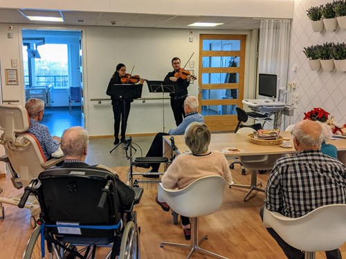 Op deze foto zie je VieCuri patiënten luisteren naar muziek van twee violisten.