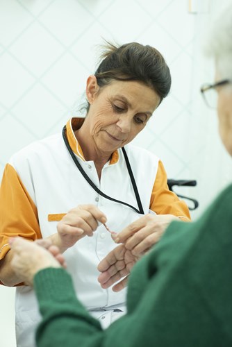 Op deze foto zie je hoe schoonmaakmedewerker Maria Hermoso de nagels lakt van een patiënt.