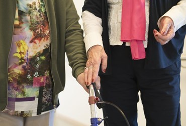 Een vrijwilligster begeleidt een oudere patiënt in het ziekenhuis