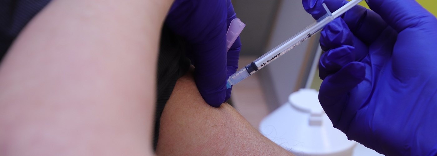 Op deze foto ziet u een close-up van een arm van iemand die wordt gevaccineerd 