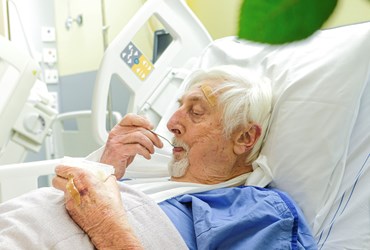 Op deze foto ziet u meneer Bogaarts in bed liggen op de verpleegafdeling. Hij eet yoghurt. 