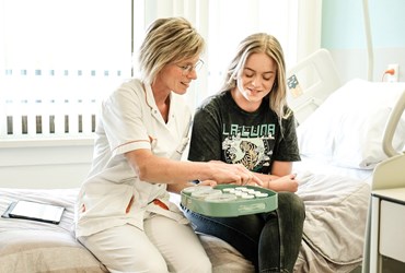 Op deze foto is een meisje en een verpleegkundige te zien in voorbereiding op een pindatest.