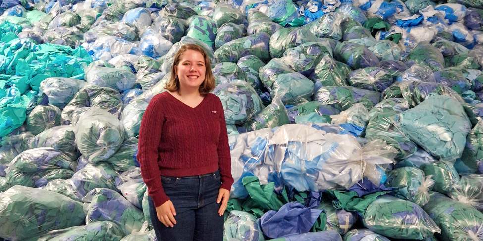 Isabella Klarenbeek, onderzoeker duurzaamheid staat bij een berg vuilniszakken