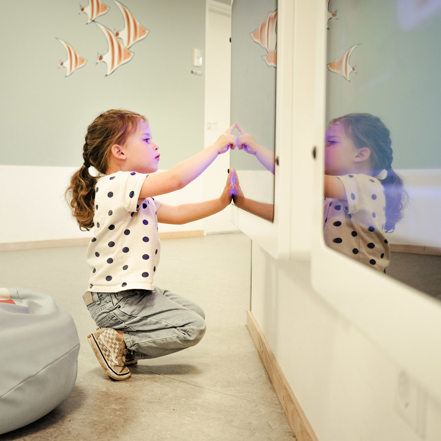 Een kind dat speelt op een scherm met op de achtergrond getekende vissen op de muur. Een kind dat speelt op een scherm met op de achtergrond getekende vissen op de muur.