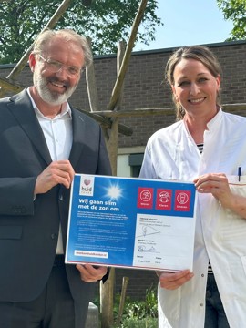 In de tuin van het Oncologiecentrum van VieCuri tonen IJsbrand Schouten en Karen van Poppelen trots het ondertekende Zonvenant