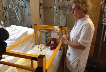 Verpleegkundige bij kinderbedje met webcam