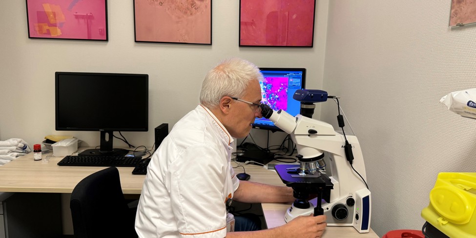 Reumatoloog Tim Jansen kijkt door een microscoop