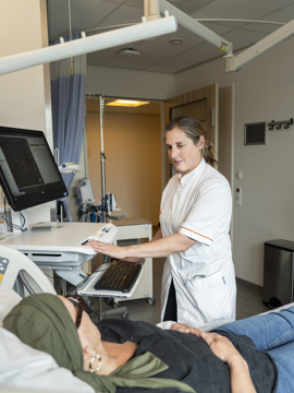Oncoloog Philo Werner staat bij een patient op de kamer. 
