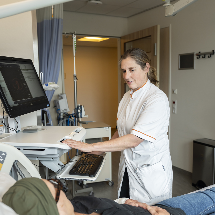 Oncoloog Philo Werner staat bij een patient op de kamer. 