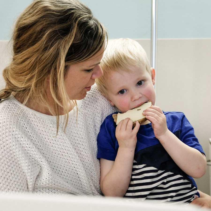 Kind eet boterham op schoot van moeder. Kind eet boterham op schoot van moeder.