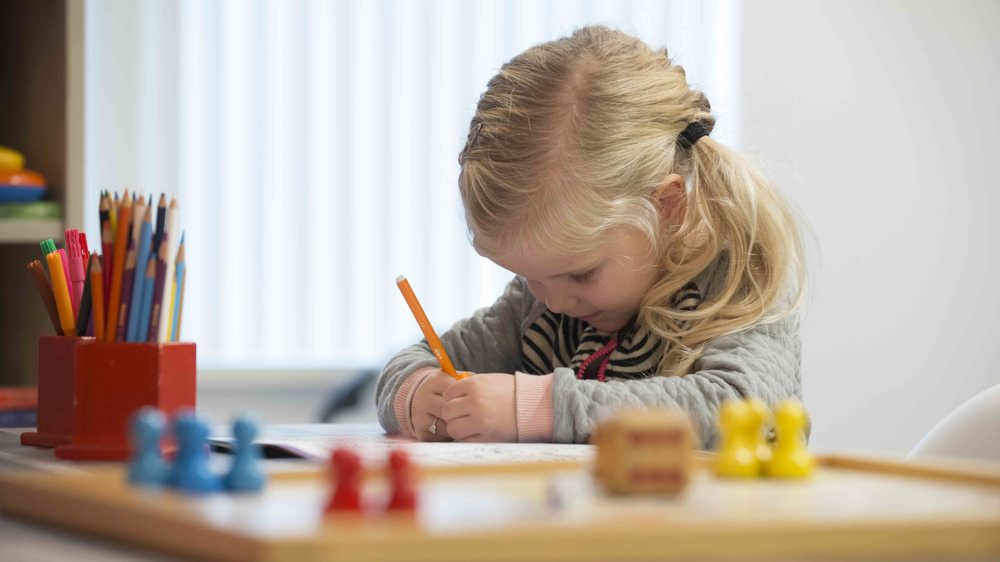 Kind tekent aan tafel Kind tekent aan tafel