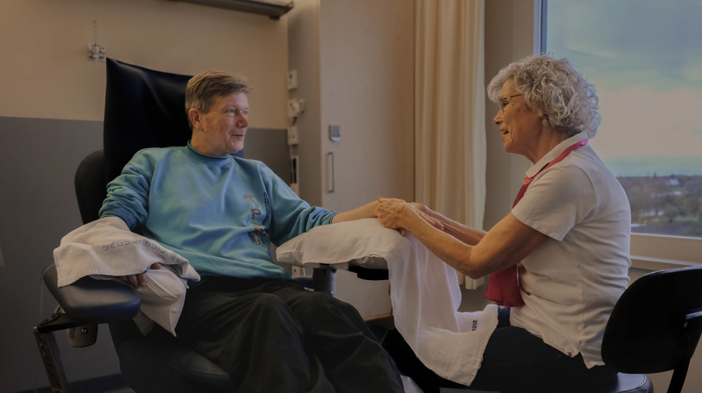 Vrijwilliger Door geeft patiënt een handmassage Vrijwilliger Door geeft patiënt een handmassage