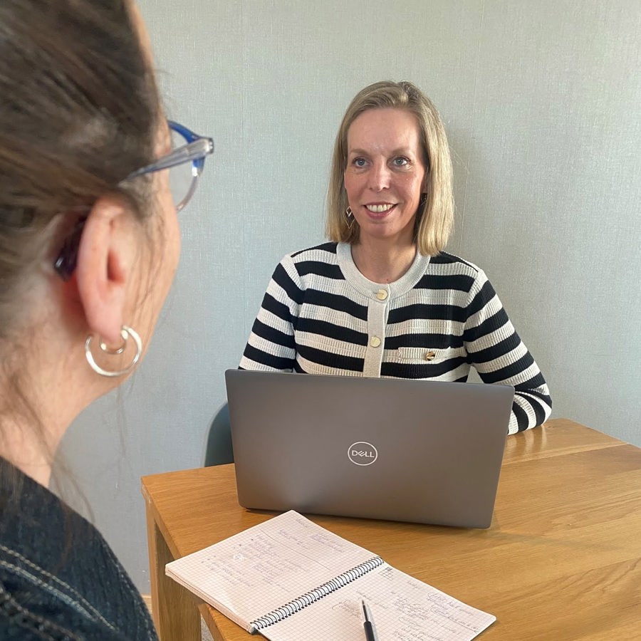 Inge de Leeuw is in gesprek met een collega en heeft haar laptop voor zich