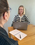 Inge de Leeuw is in gesprek met een collega en heeft haar laptop voor zich