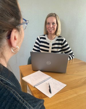 Inge de Leeuw is in gesprek met een collega en heeft haar laptop voor zich