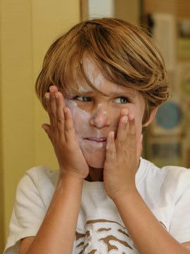 Jongen smeert zich in met zonnebrnadcreme Jongen smeert zich in met zonnebrnadcreme