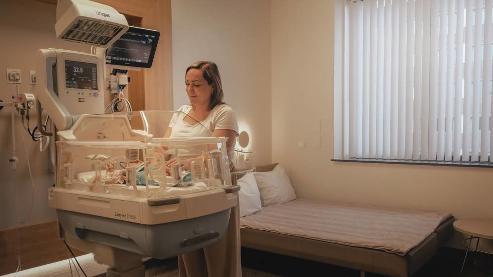 Moeder bij baby in couveuse op afdeling Neonatologie.