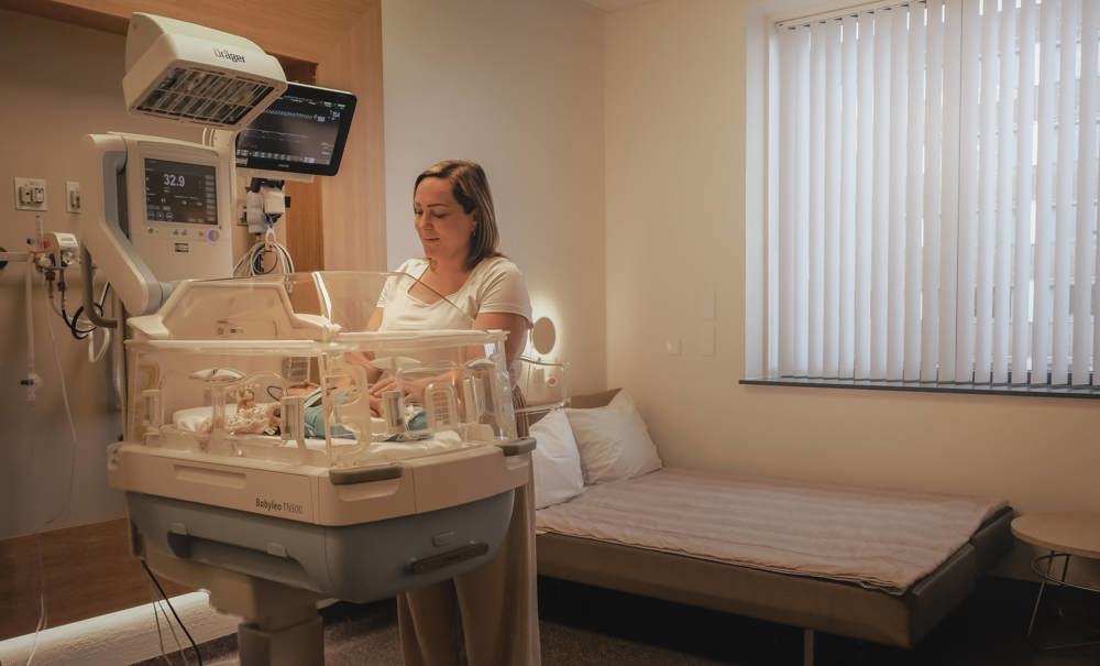 Moeder bij baby in couveuse op afdeling Neonatologie.