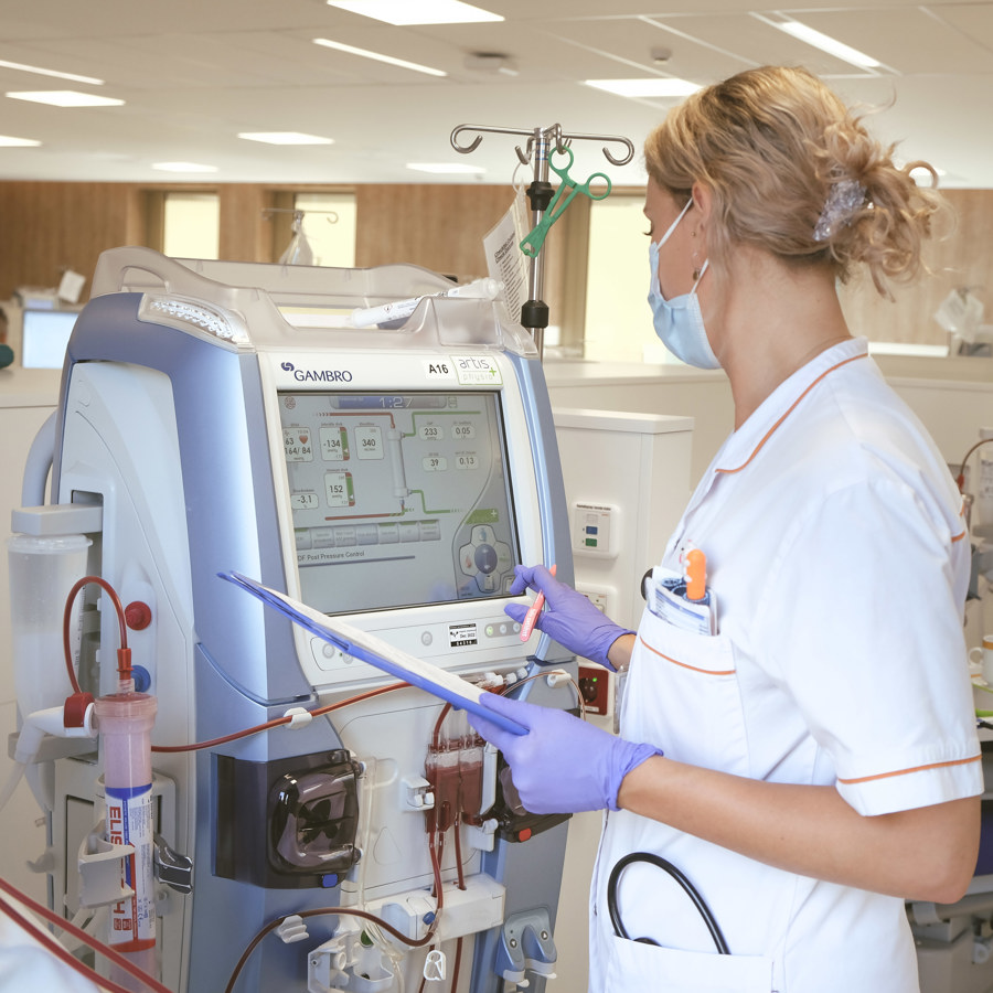 Dialyseverpleegkundige controleert gegevens op dialyseapparaat Dialyseverpleegkundige controleert gegevens op dialyseapparaat
