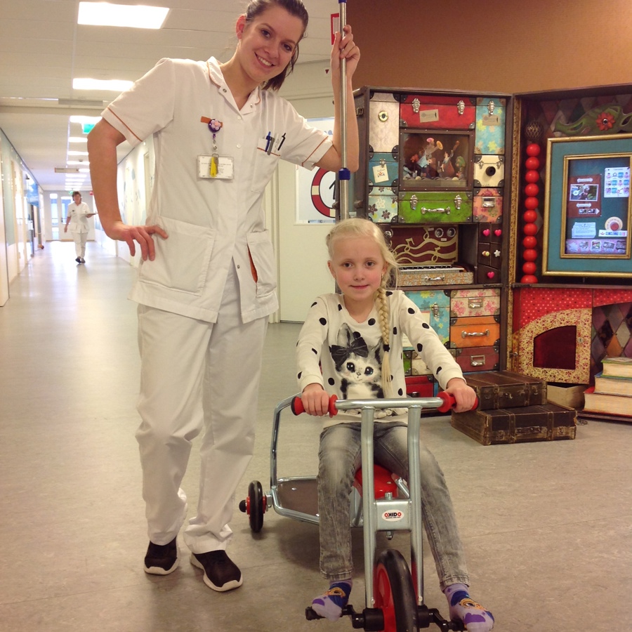 Kinderverpleegkundige en kind op fietsje Kinderverpleegkundige en kind op fietsje