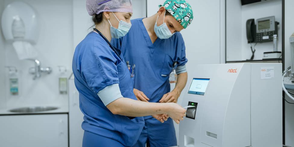 Een chirurg en anesthesiemedewerker kijken naar de uitslag van de PTH meter op de OK