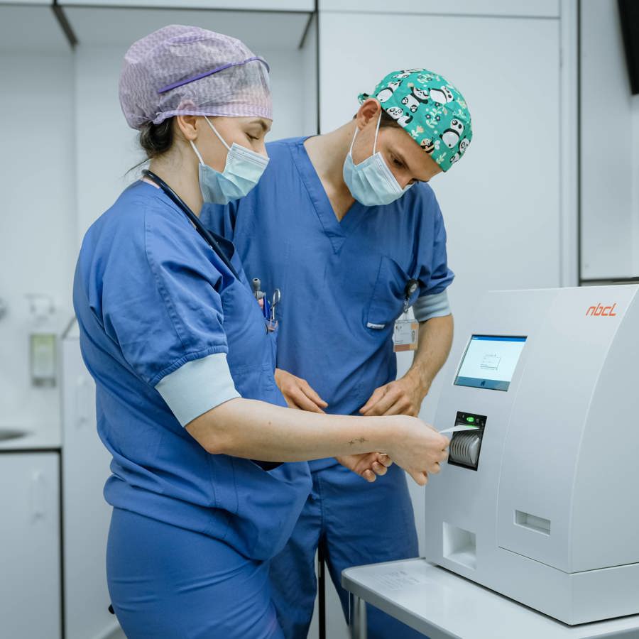 Een chirurg en anesthesiemedewerker kijken naar de uitslag van de PTH meter op de OK