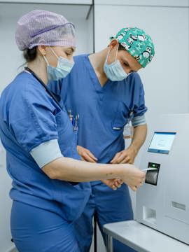 Een chirurg en anesthesiemedewerker kijken naar de uitslag van de PTH meter op de OK Een chirurg en anesthesiemedewerker kijken naar de uitslag van de PTH meter op de OK