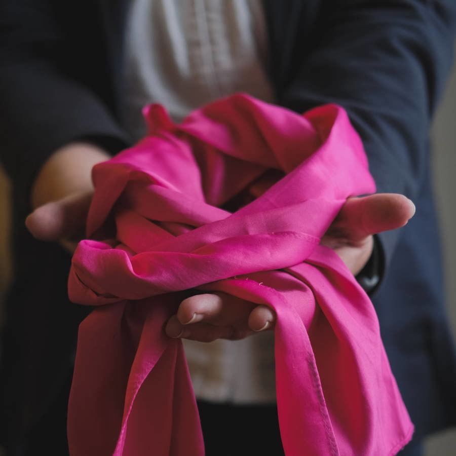 Opengestelde hand met daarin een roze sjaal welke wordt gedragen door de vrijwilligers van VieCuri