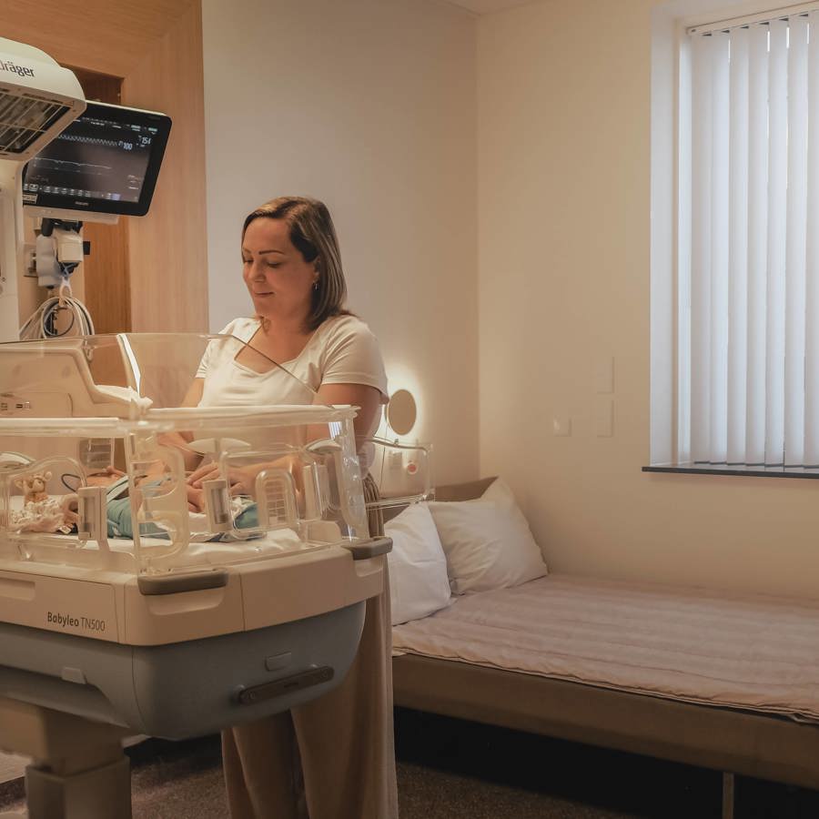 Moeder bij baby in couveuse