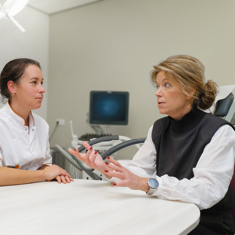 Arts in overleg met patiënt in spreekkamer Arts in overleg met patiënt in spreekkamer