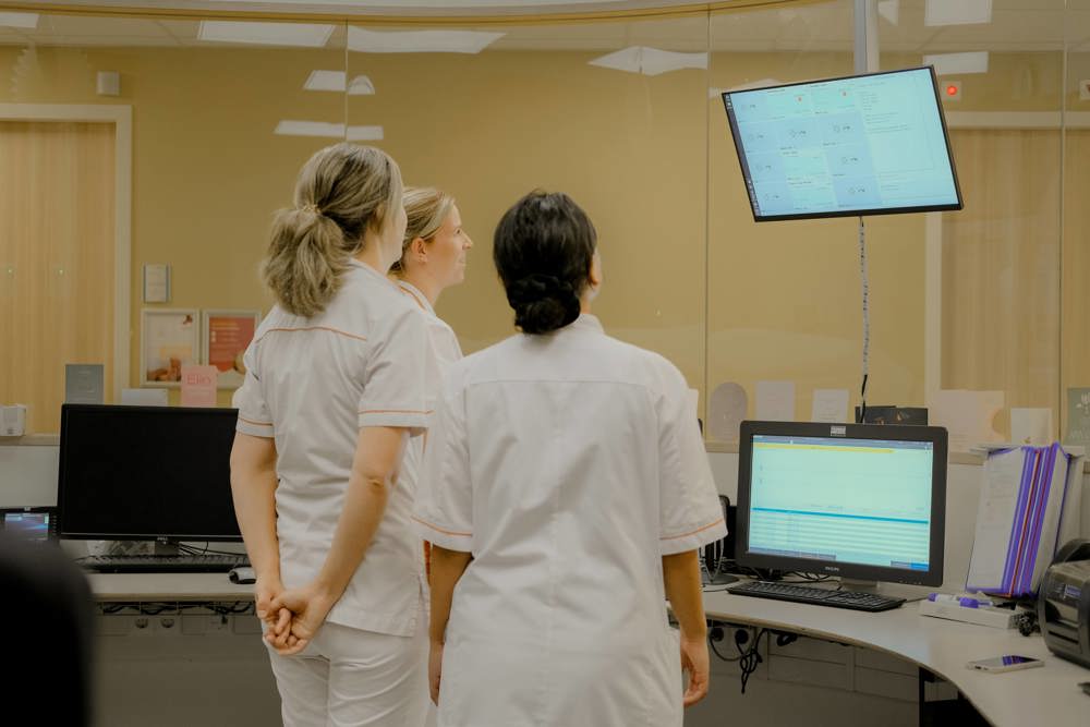 Verpleegkundigen in de verpleegpost op afdeling Neonatologie/ Couveusesuite, kijken op scherm.